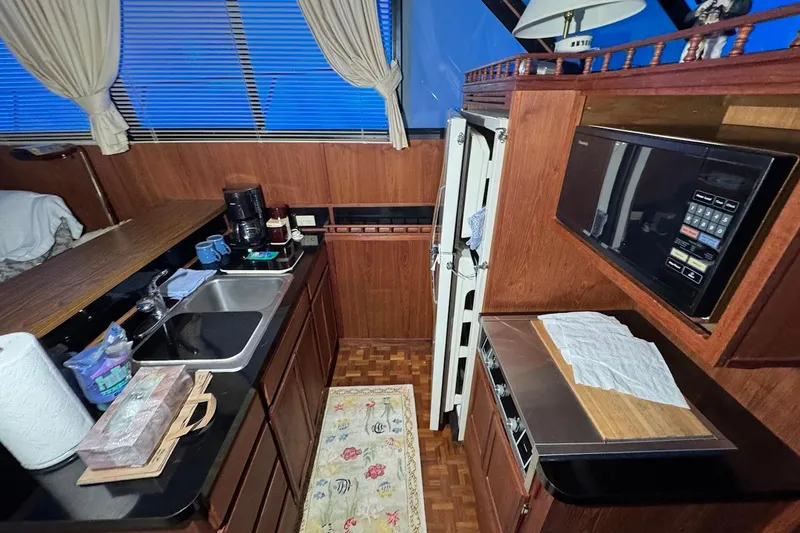 Slide: The Image of 1986 Bluewater 46 MY yacht kitchen with wood cabinetry, sink, microwave, and appliances. - 9