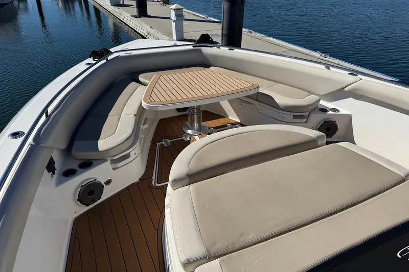 Slide: The Image of 2020 Boston Whaler 420 Outrage boat interior with cushioned seating and wooden table. - 12
