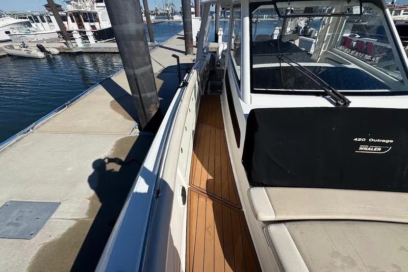 Slide: The Image of 2020 Boston Whaler 420 Outrage docked, showcasing sleek design and spacious deck. - 18