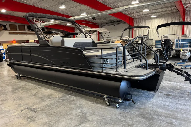 Slide: The Image of 2026 Sylvan L-5 Platinum pontoon boat in showroom, featuring sleek black design. - 8