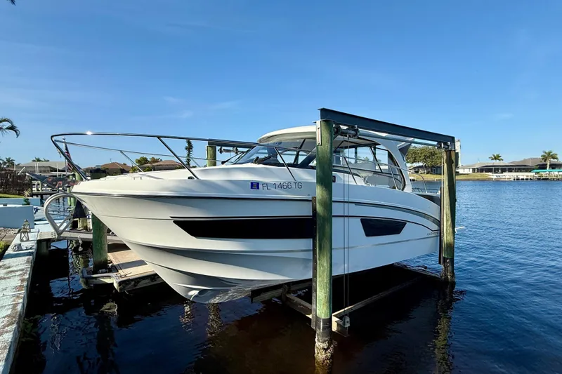 Slide: The Image of 2022 Beneteau Antares 9 boat docked on a lift by the water. - 1