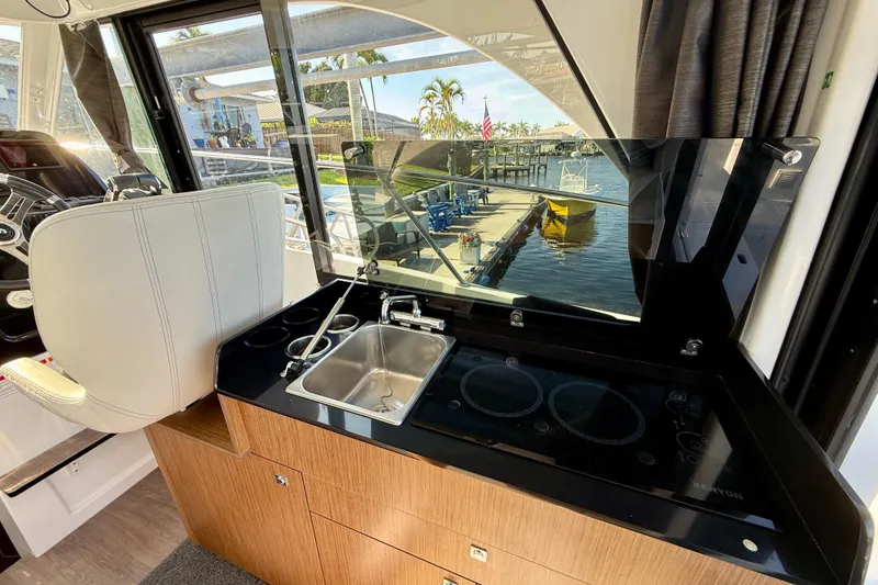 Slide: The Image of Interior of 2022 Beneteau Antares 9, featuring a compact kitchen with sink and stove. - 15