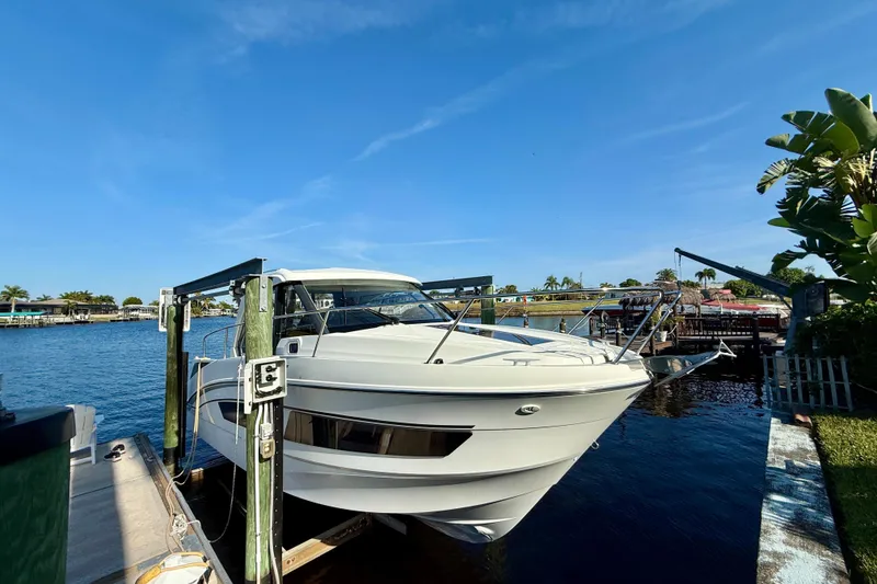 Slide: The Image of 2022 Beneteau Antares 9 docked by a scenic waterfront under a clear blue sky. - 2