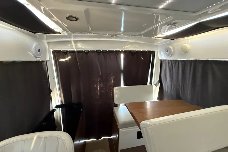 Slide: The Image of Interior of 2022 Beneteau Antares 9 with seating and table, curtains drawn. - 6