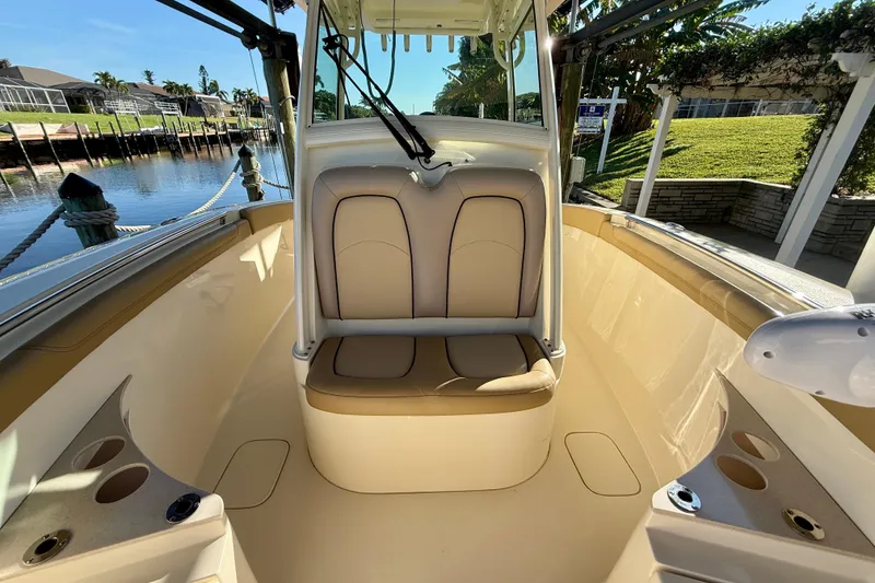 Slide: The Image of 2016 Scout 255 LXF boat interior with seating and cup holders, docked by a canal. - 17