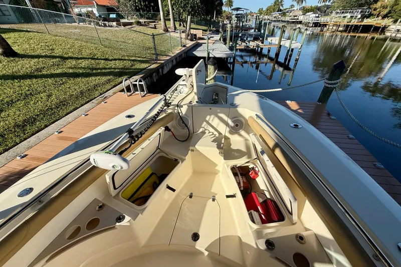 Slide: The Image of 2016 Scout 255 LXF boat docked by a serene waterfront with open storage compartments. - 19