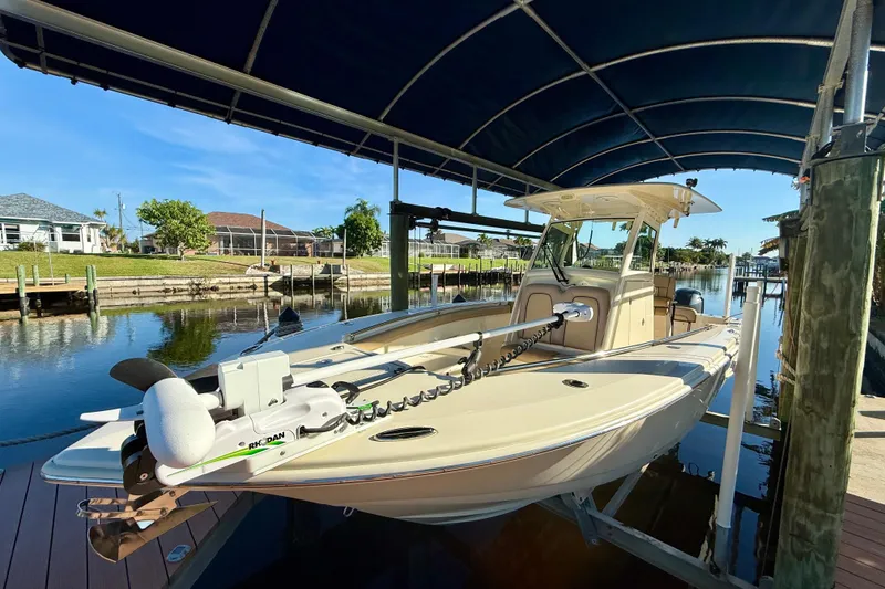 Slide: The Image of 2016 Scout 255 LXF boat docked under a canopy in a scenic canal. - 23