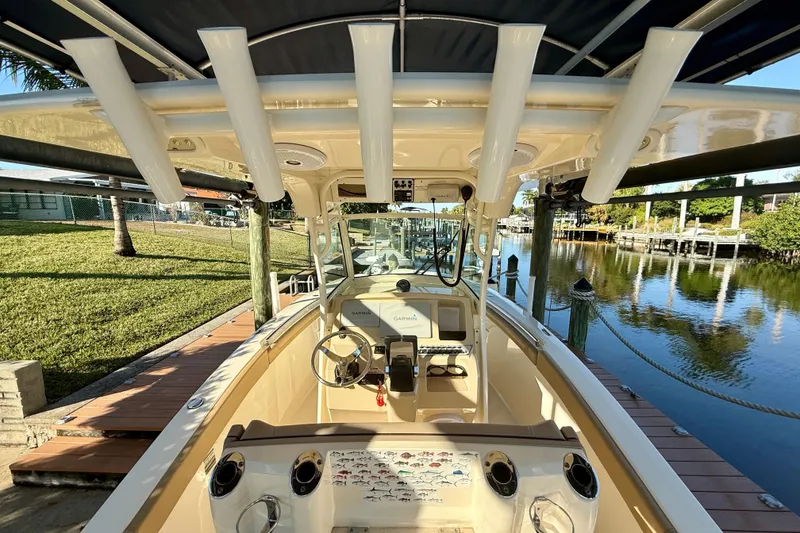 Slide: The Image of 2016 Scout 255 LXF boat interior with steering wheel and rod holders, docked by a serene canal. - 24