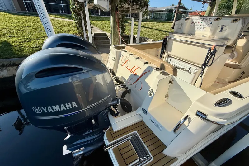 Slide: The Image of 2016 Scout 255 LXF boat with Yamaha outboard engines, docked near a grassy area. - 5