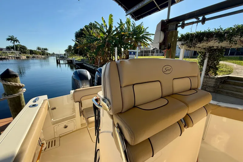 Slide: The Image of 2016 Scout 255 LXF boat interior with dual engines, docked by a scenic canal. - 7