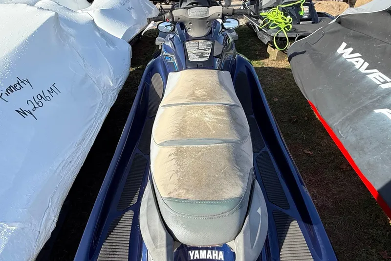 Slide: The Image of 2014 Yamaha WaveRunner VX Deluxe jet ski with worn seat, parked outdoors. - 4