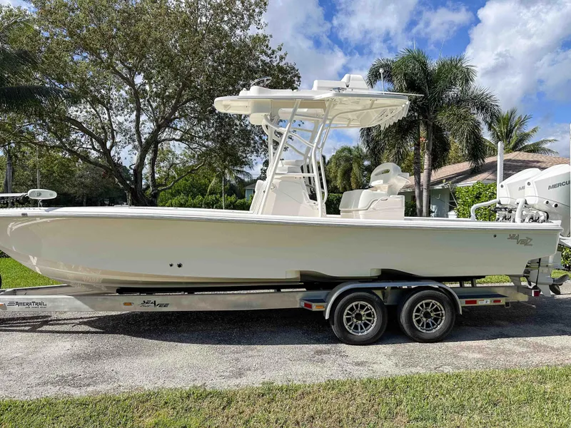 Slide: The Image of 2022 SeaVee 270Z boat on trailer, parked outdoors with trees in the background. - 2