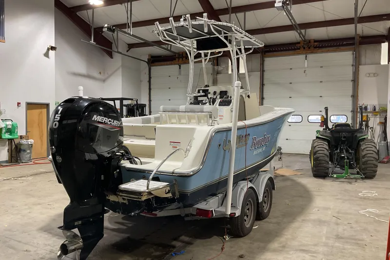 Slide: The Image of 2022 Mako 214 Center Console boat in a garage with Mercury engine. - 4