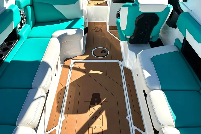 Slide: The Image of 2021 Axis A24 boat interior with teal and white seating, brown flooring, and cup holders. - 39