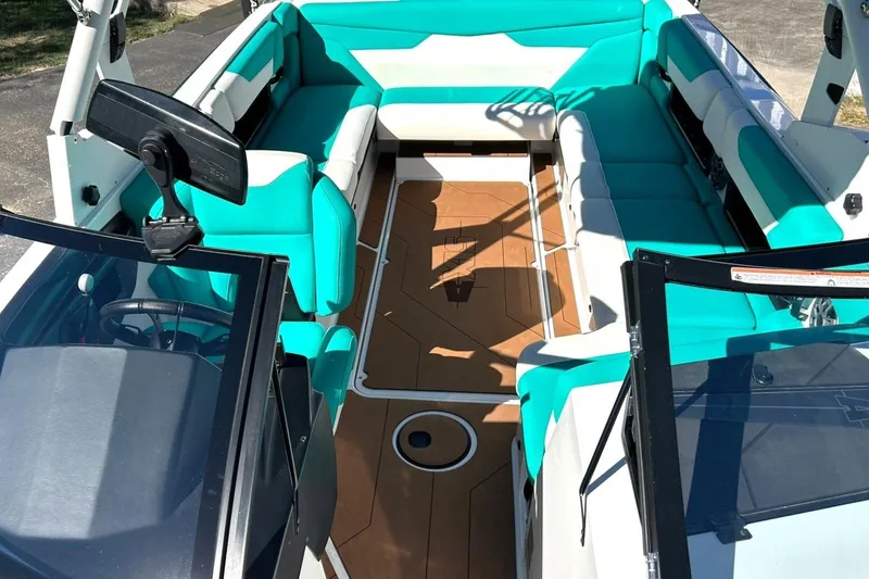 Slide: The Image of 2021 Axis A24 boat interior with teal and white seating, brown flooring, and steering console. - 4