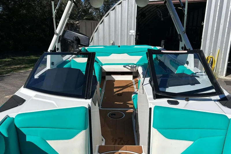 Slide: The Image of 2021 Axis A24 boat with teal seating and open cockpit, parked near a metal building. - 45