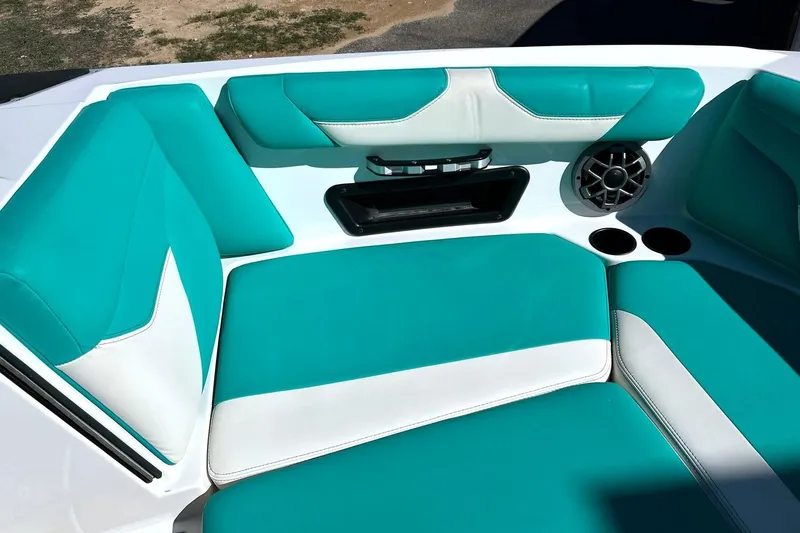 Slide: The Image of 2021 Axis A24 boat interior with teal and white seating, speaker, and cup holders. - 49
