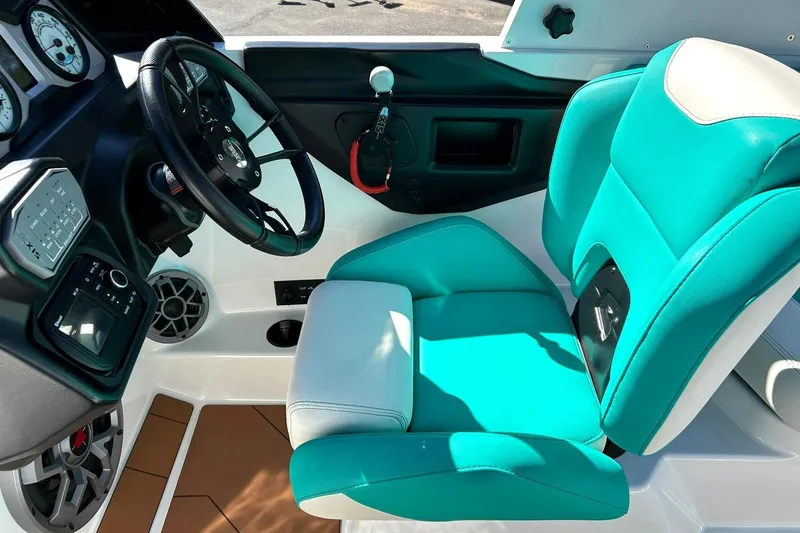 Slide: The Image of 2021 Axis A24 boat interior with teal and white seating, steering wheel, and dashboard controls. - 5