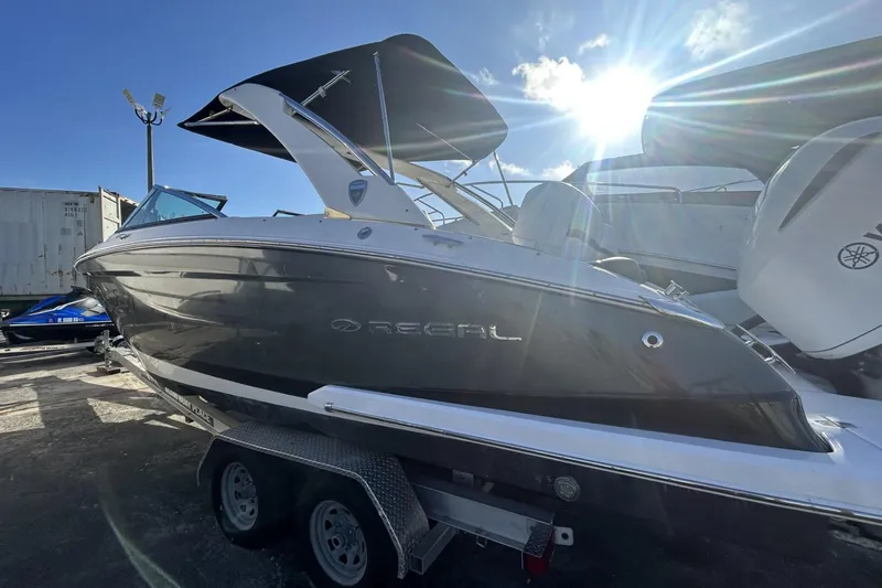 Slide: The Image of 2017 Regal 2900 Bowrider boat with black hull, parked on a trailer under sunny sky. - 4