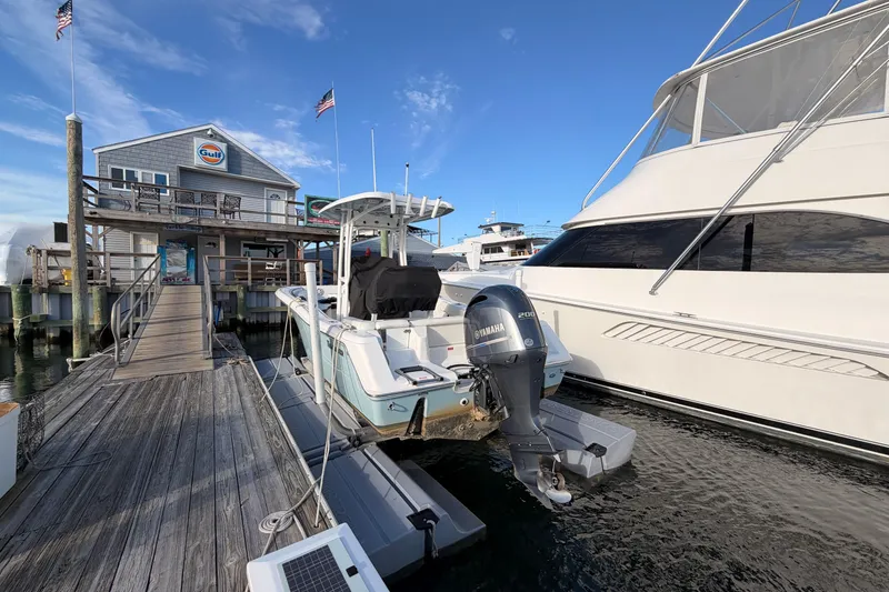 Slide: The Image of 2022 Tidewater 220 LXF boat docked with Yamaha 200 engine, near Gulf station. - 2