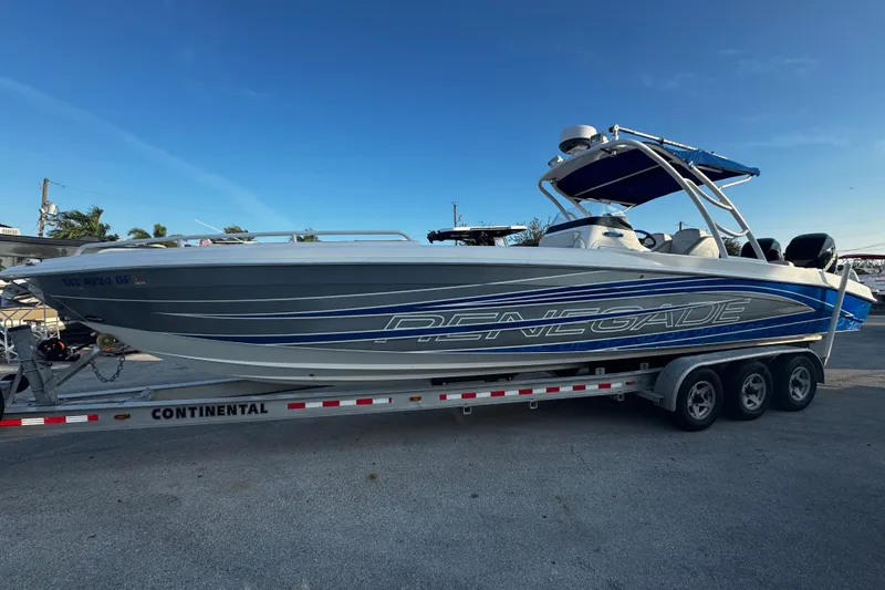 Slide: The Image of 2012 Renegade 32 CC boat on trailer, side view, blue and white design. - 2