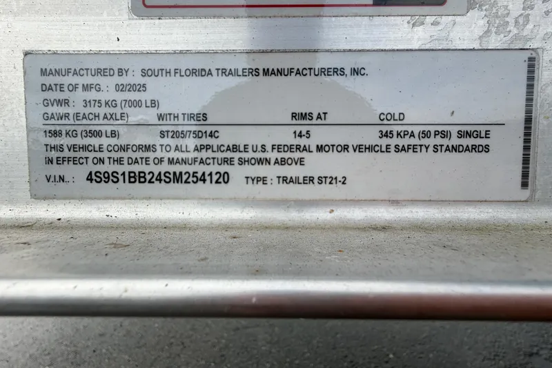 Slide: The Image of 2025 Sea Hunt Ultra 219 boat with T-top, parked outdoors under clear blue sky. - 43