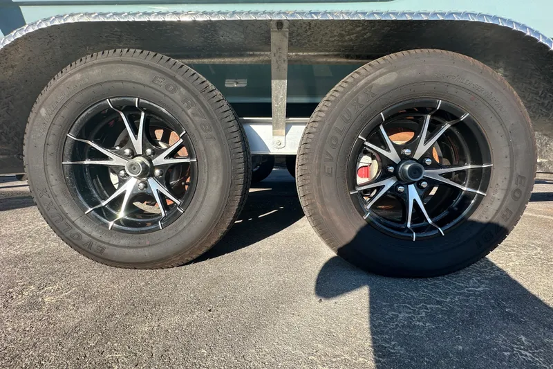 Slide: The Image of Trailer wheels of a 2025 Sea Hunt Ultra 219 boat on pavement. - 70