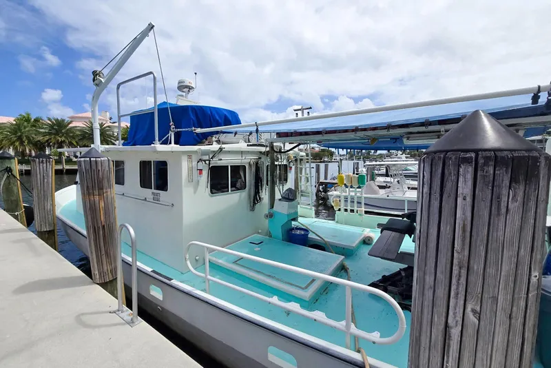 Slide: The Image of 1996 Lafitte Skiff 48 docked, featuring a spacious deck and blue canopy. - 2