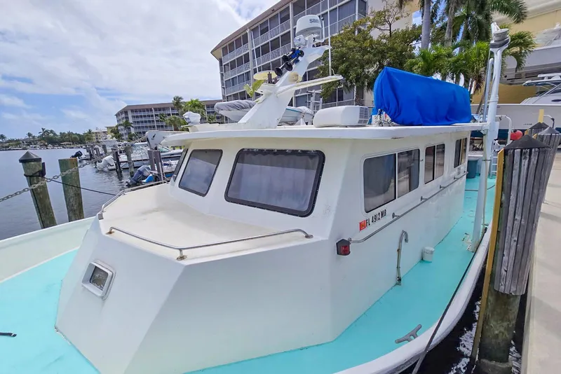 Slide: The Image of 1996 Lafitte Skiff 48 docked at marina with blue cover and modern equipment. - 4