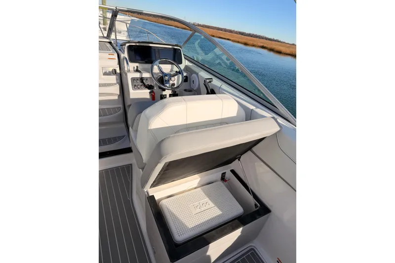 Slide: The Image of 2022 Regal 26 XO boat helm with storage compartment, steering wheel, and water view. - 12