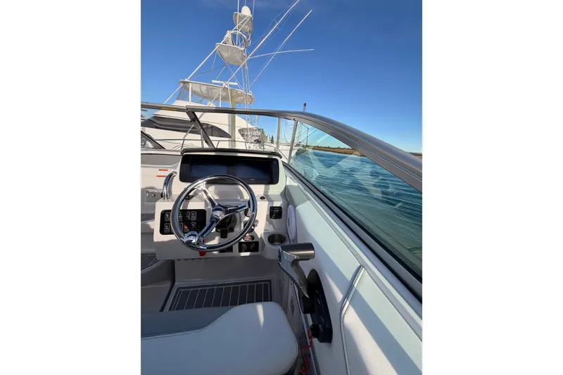 Slide: The Image of 2022 Regal 26 XO boat helm with steering wheel and controls, on calm water. - 21