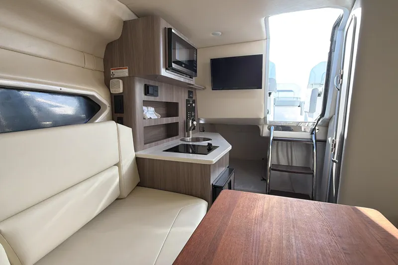 Slide: The Image of 2022 Regal 26 XO boat interior with kitchenette, seating, and ladder access. - 26