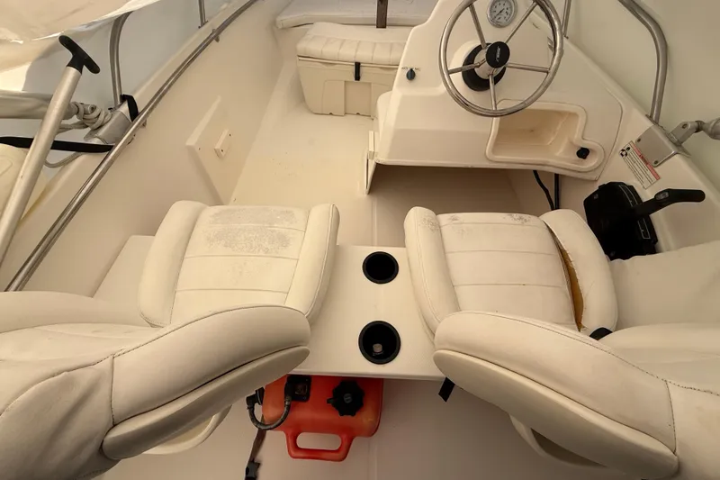 Slide: The Image of 2011 Boston Whaler 150 Super Sport interior with white seating and steering wheel. - 11