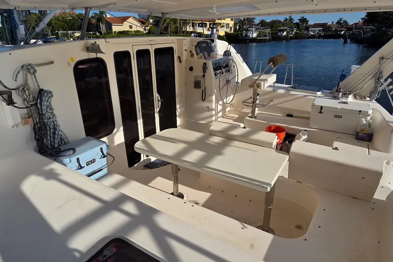 Slide: The Image of 2004 Leopard 47 catamaran cockpit with seating, table, and waterfront view. - 16