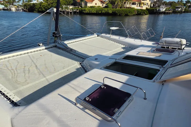 Slide: The Image of 2004 Leopard 47 catamaran deck with open hatches, docked by waterfront homes. - 19