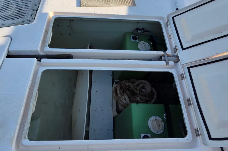 Slide: The Image of Open storage compartments on a 2004 Leopard 47 catamaran, featuring green tanks and coiled rope. - 20
