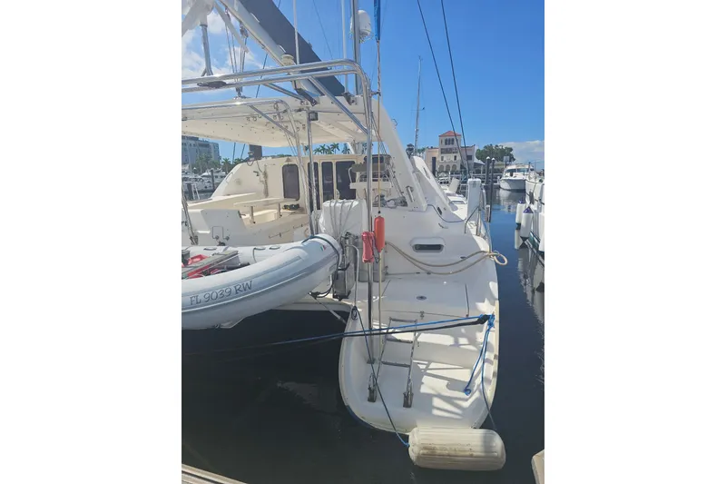 Slide: The Image of 2004 Leopard 47 catamaran docked at marina, featuring inflatable dinghy and clear blue sky. - 3