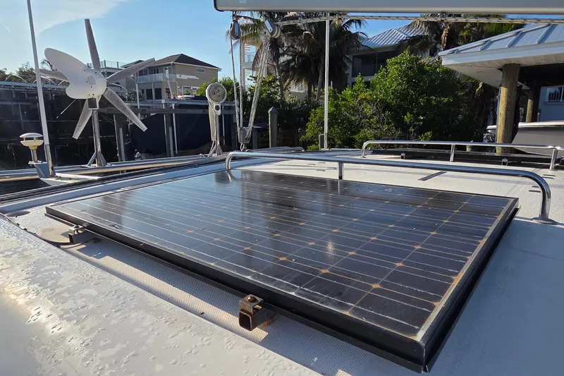 Slide: The Image of Solar panel on 2004 Leopard 47 catamaran, with wind turbine, docked near greenery. - 32