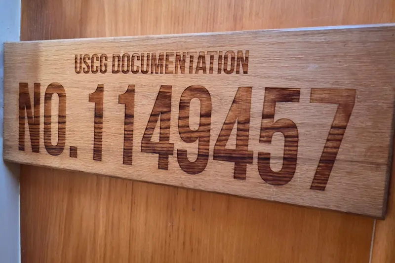 Slide: The Image of USCG documentation plaque with number 1149457 on wooden background. - 73