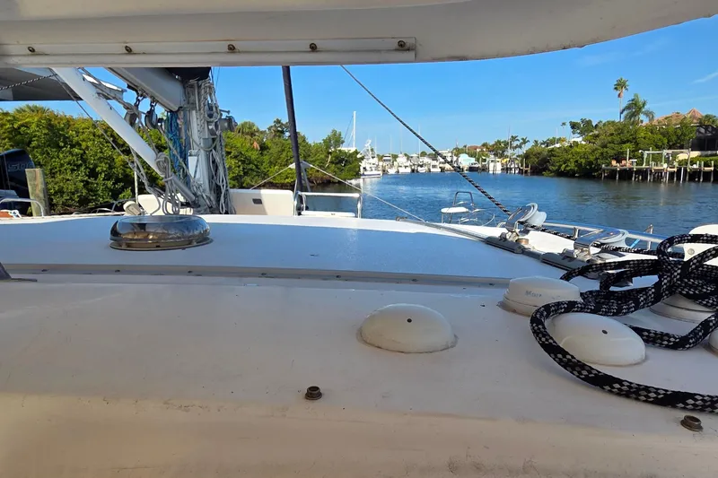 Slide: The Image of 2004 Leopard 47 catamaran on a serene waterway, surrounded by lush greenery and clear skies. - 75