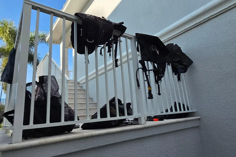 Slide: The Image of Diving gear drying on a white railing, with palm trees and stairs in the background. - 77