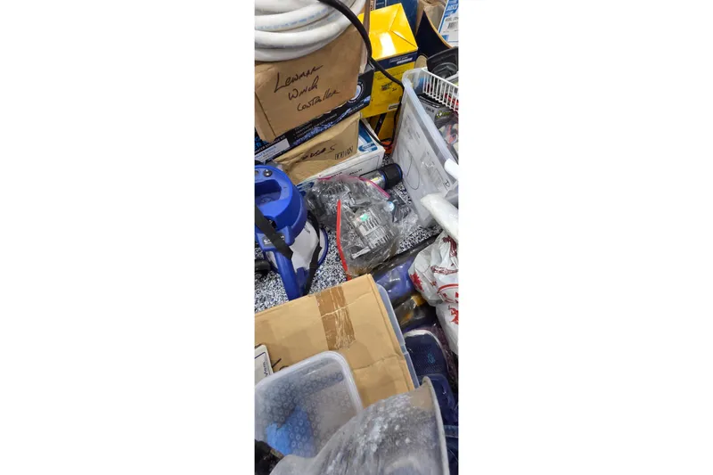 Slide: The Image of Cluttered storage area with various boxes and equipment, including a blue tool and labeled containers. - 88