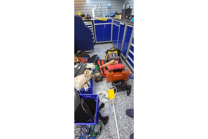 Slide: The Image of Workshop with tools and equipment, featuring blue cabinets and various cables on the floor. - 92