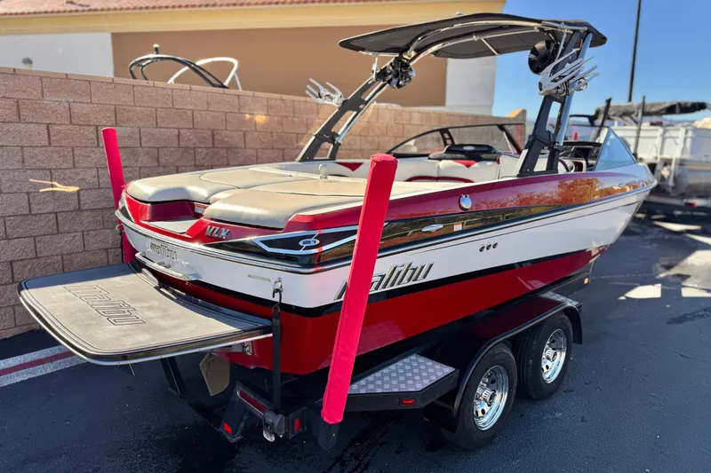 Slide: The Image of 2012 Malibu Wakesetter 21 VLX boat on trailer, red and white design, parked outdoors. - 5