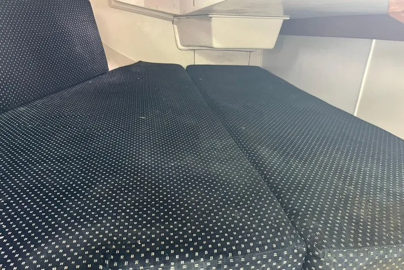 Slide: The Image of Interior seating of a 2003 Catalina 30 sailboat with dark patterned upholstery. - 12