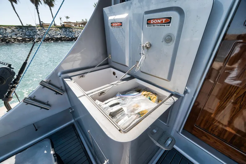 Slide: The Image of 2004 Guthrie 60 Custom Carolina boat with open storage compartment by the water. - 59