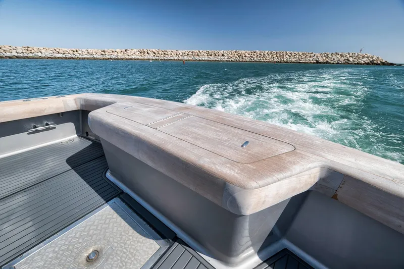 Slide: The Image of 2004 Guthrie 60 Custom Carolina boat cruising on blue ocean near rocky breakwater. - 63