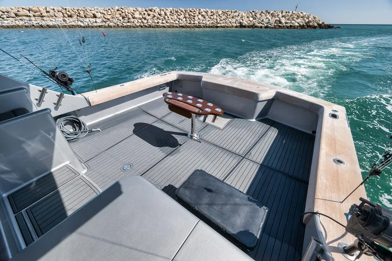 Slide: The Image of 2004 Guthrie 60 Custom Carolina boat deck with fishing rods, ocean view, and rocky breakwater. - 64