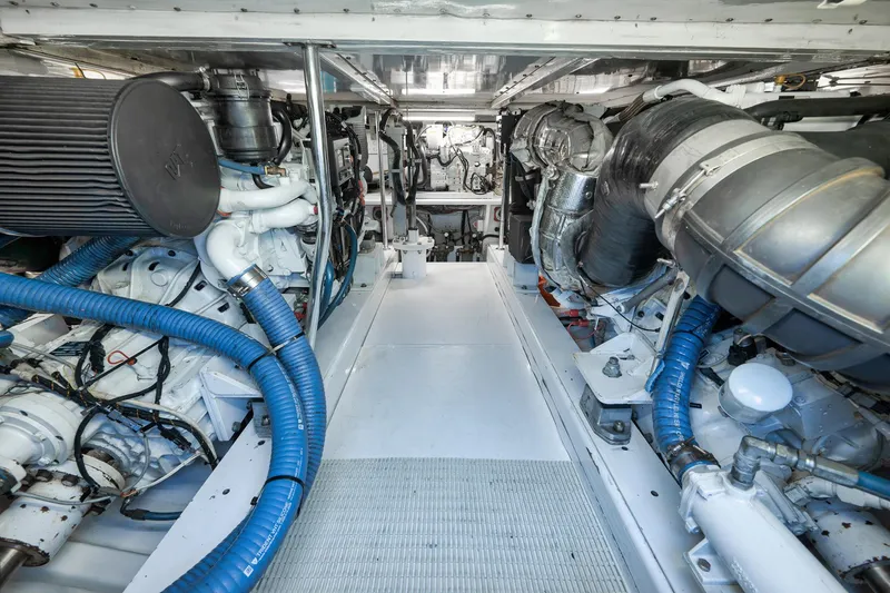 Slide: The Image of Engine room of 2004 Guthrie 60 Custom Carolina boat, featuring complex machinery and blue hoses. - 66