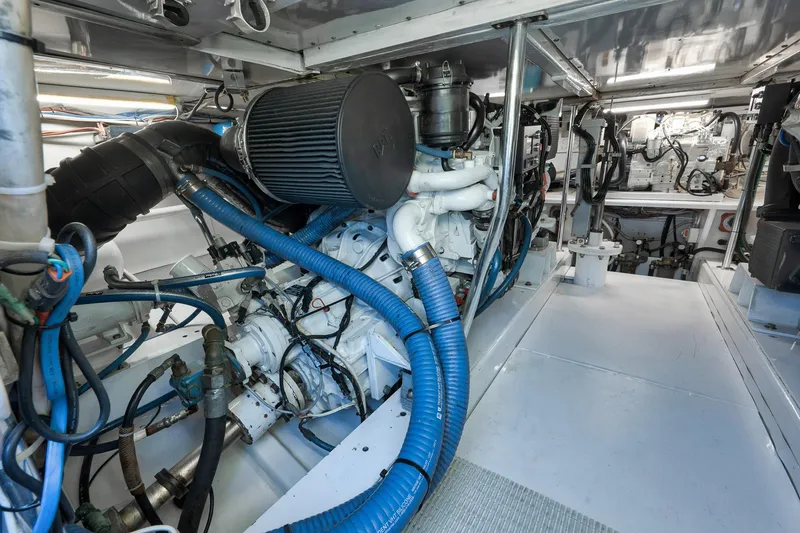 Slide: The Image of Engine room of 2004 Guthrie 60 Custom Carolina boat, featuring complex machinery and blue hoses. - 67